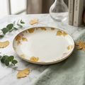 Decorative ceramic plate with floral design on a marble surface with leaves and a spoon.
